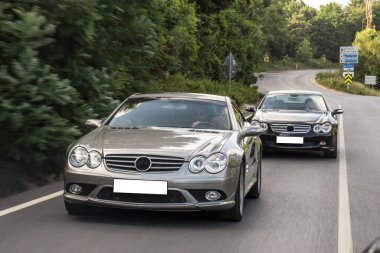 Gün batımında gümüş yarış arabası sürücüsü, arabaları kovalıyor.