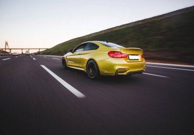 Sarı spor sedan arazi aracı tepeleri aşıyor.
