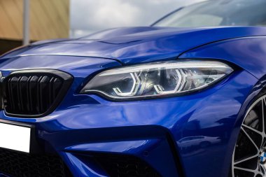 Mavi sedan park yeri, ön ışık ve tampon manzarası.