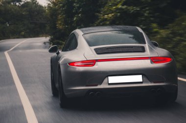 Orman yolunda siyah çatılı bronz spor araba.