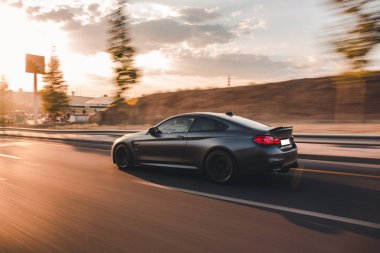 Yeni model siyah sedan. Günbatımında hızlı bir sürüş, arkadan görüş.