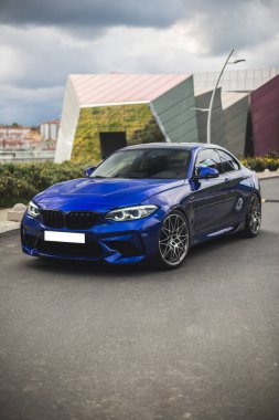 Dışarıdaki mavi sedan, panoramik binalar manzaralı.