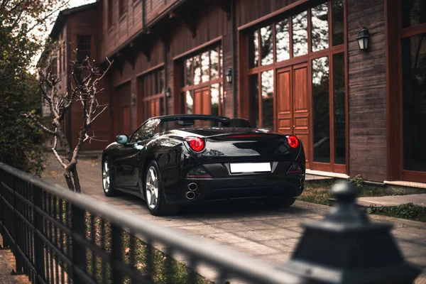 Black sedan car parked in front of a red apartment — Stock Photo, Image