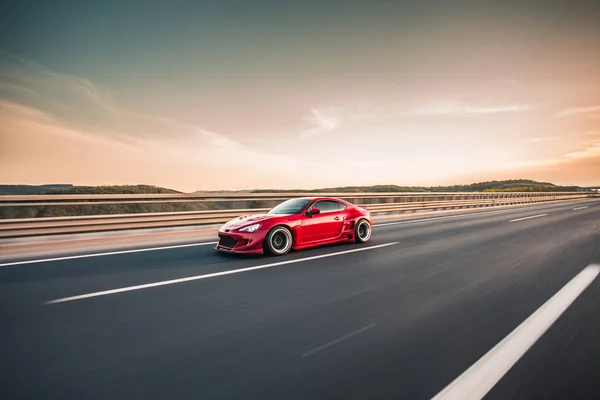 Red racing car on the vast grand highway — Stock Photo, Image