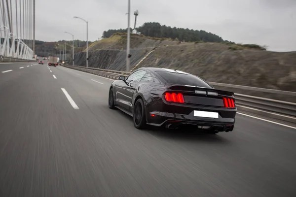 Driving a black car on the freeway across green mountains, view from behind — Stock Photo, Image