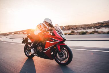 Günbatımında yüksek hızda kırmızı bir motosiklet sürmek