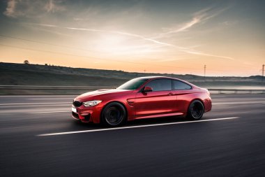 Bulanık hız görüntüsü, gün batımında kırmızı yarış arabası.