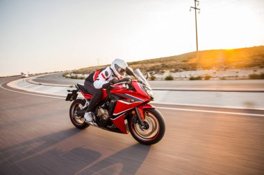 Gün batımında kırmızı bir motosiklet sürmek