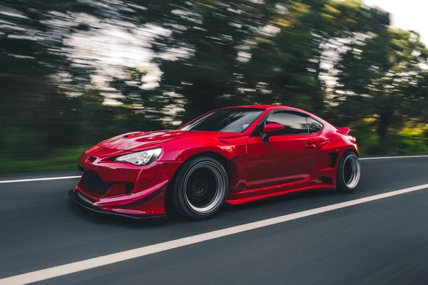 Superpower red car racing in the forest road — Stock Photo, Image