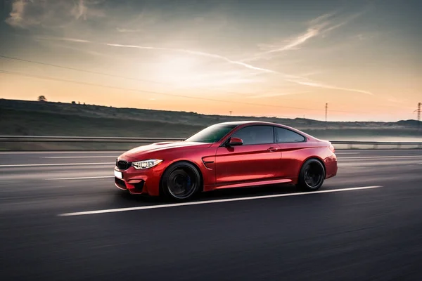 Gün batımında kırsal bir alanda kırmızı spor taksi.