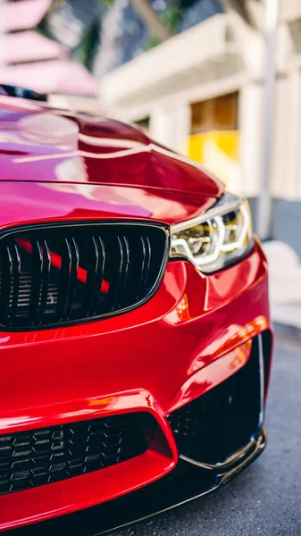 Sedán modelo rojo en el estacionamiento emblemático, luz frontal y vista al parachoques —  Fotos de Stock