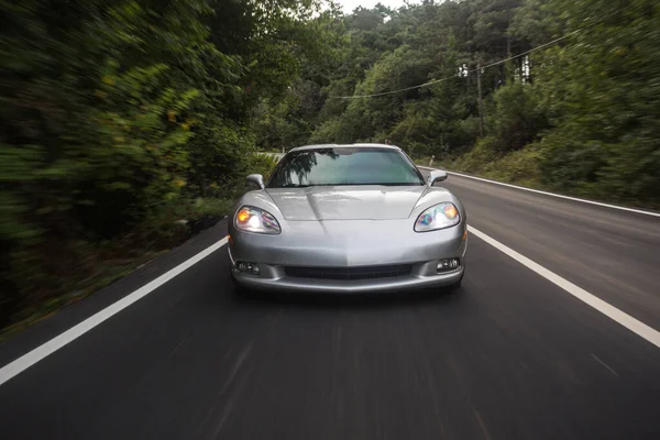 Teste de desempenho de velocidade de supercarro de prata, estrada vazia, tempo escuro, luzes dianteiras ligadas — Fotografia de Stock