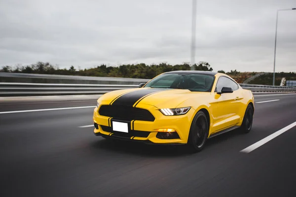 Yellow sport car with black stripe in the racing track over the landscapes — Stock Photo, Image