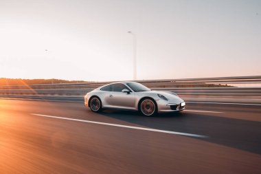 Dağ yollarında gün ışığıyla aydınlatılmış gümüş bir sedan.