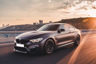 Yeni model siyah sedan gün batımında hızlı sürüşte