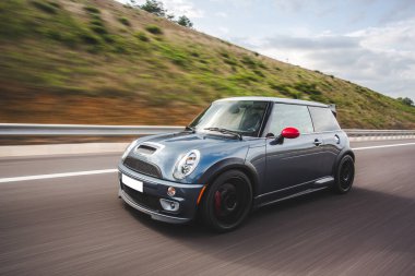 Dağlık arazide mavi bir süper araba otostop yapıyor.