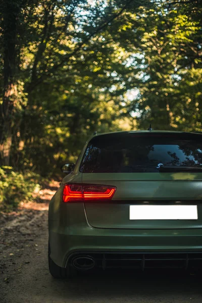 Sedan azul com luzes de xenônio vermelho na floresta — Fotografia de Stock