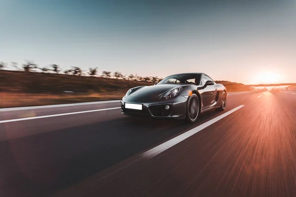 Azul marino coche deportivo velocidad de conducción en la autopista en la puesta del sol —  Fotos de Stock