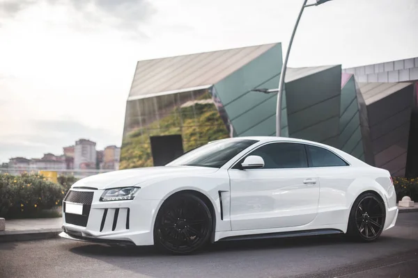 Witte sport sedan geparkeerd over kantoorgebouwen in een mistige weer — Stockfoto