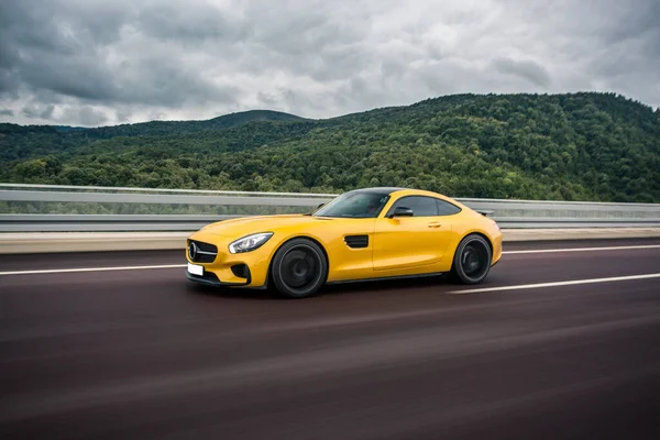 Color amarillo tecnología moderna modelo deportivo coche en una carretera bajo las nubes — Foto de Stock