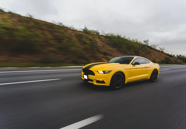 Yellow sport car with black stripe in the racing track over the landscapes , front view — Stock Photo, Image