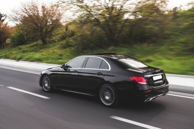 Siyah Avrupa model sedan yeşil alanlarda ilerliyor