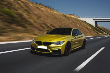 Sarı sedan güneşli bir günde çöl tepelerinden geçiyor.