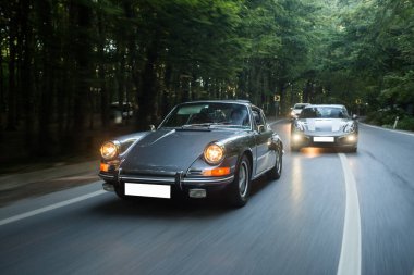 Arkadaki bir araba orman yolunda ilk arabayı geçmek için ön ışıkları yaktı.