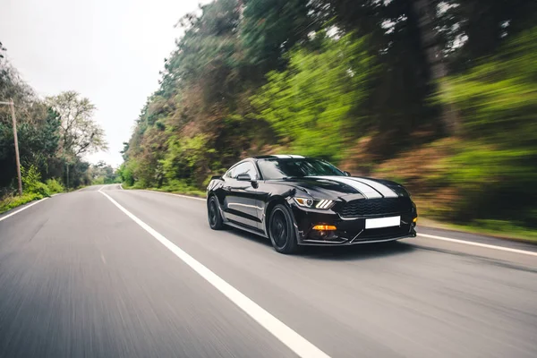 Black sport sedan with white autotuning in the countryside, blurred forest view — Stock Photo, Image