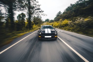 Otobanda beyaz otomatik kumandalı siyah spor bir sedan.