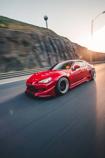 Vermelho elegante carro esporte carro paisagem unidade no pôr do sol — Fotografia de Stock