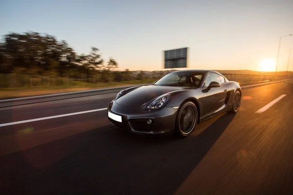 Azul marino coche deportivo velocidad de conducción en la autopista en el atardecer — Foto de Stock