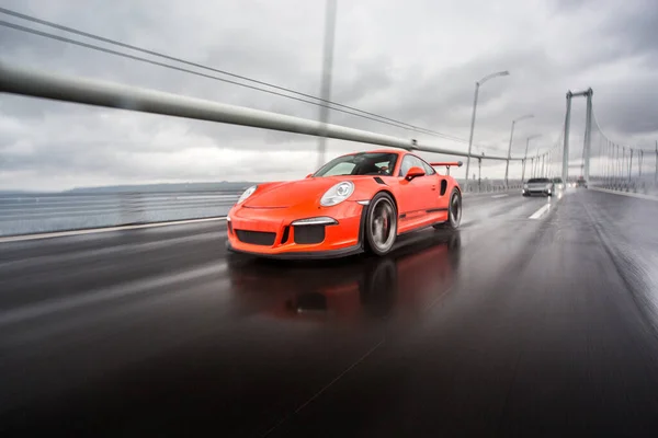 Cor vermelha moderna tecnologia esporte modelo carro em uma rodovia em um clima chuvoso — Fotografia de Stock