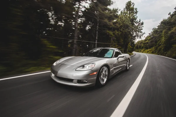 夕方の森林道路上の銀スーパーカーの速度性能 — ストック写真
