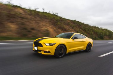 Yarış pistinde siyah çizgili sarı spor araba manzaralı.