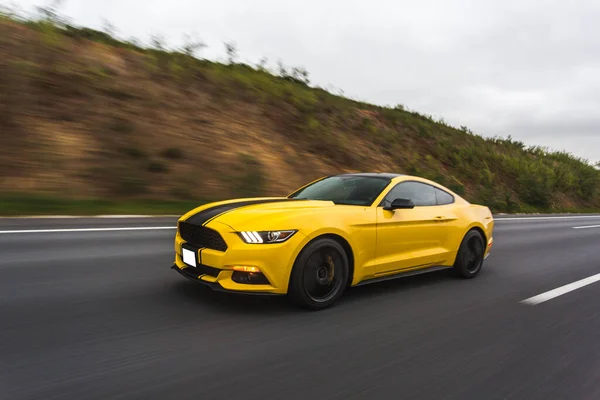 Yellow sport car with black stripe in the racing track over the landscapes, angle view — стоковое фото