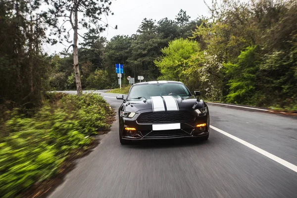 Sedan esporte preto com autotuning branco na rodovia através de territórios verdes — Fotografia de Stock