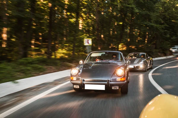 Ardından orman yolunda siyah bir klasik araba, ön ışıklar açık. — Stok fotoğraf