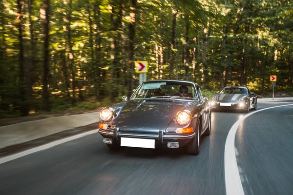 Orman yolunda siyah bir klasik araba tarafından takip ediliyor. — Stok fotoğraf
