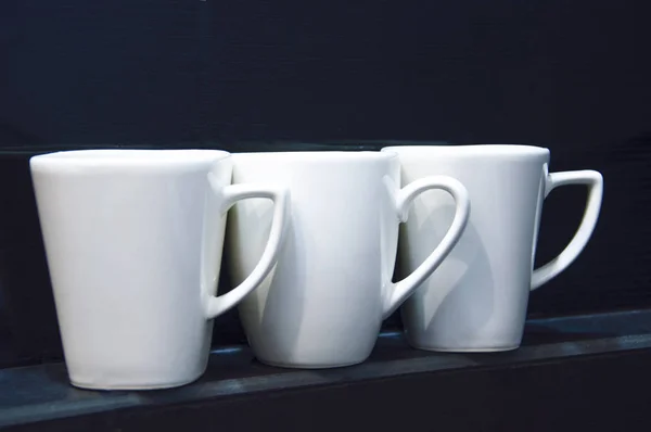 White cups on the black shelf — Stock Photo, Image