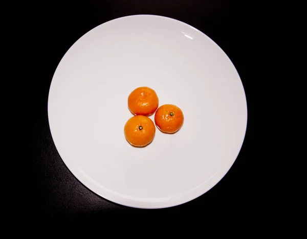 Trois mandarines sur une assiette blanche, vue du dessus — Photo