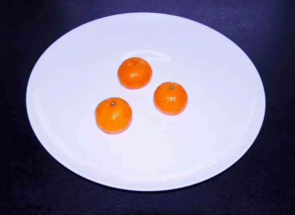 Trois mandarines sur une assiette blanche — Photo