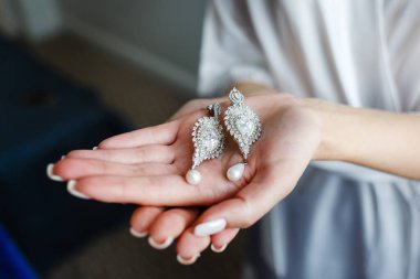 Gelinin elinde küpeler.