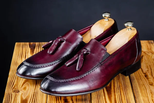 Moderna Bordeaux färg mäns loafers över svart bakgrund. Royaltyfria Stockfoton