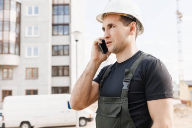 İnşaatçı cep telefonuyla konuşuyor.