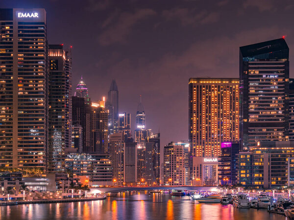 DUBAI, UAE - DECEMBER 8, 2019: ground level night shoot of Dubai Marina water canal and skyscrapers with luminous windows.