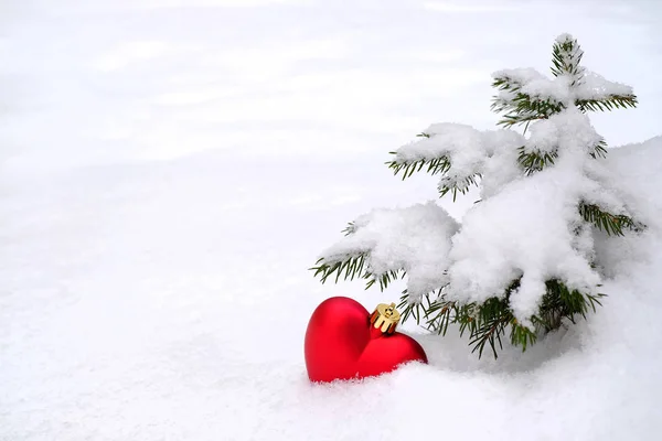 Coração de brinquedo vermelho na árvore de Natal na neve — Fotografia de Stock