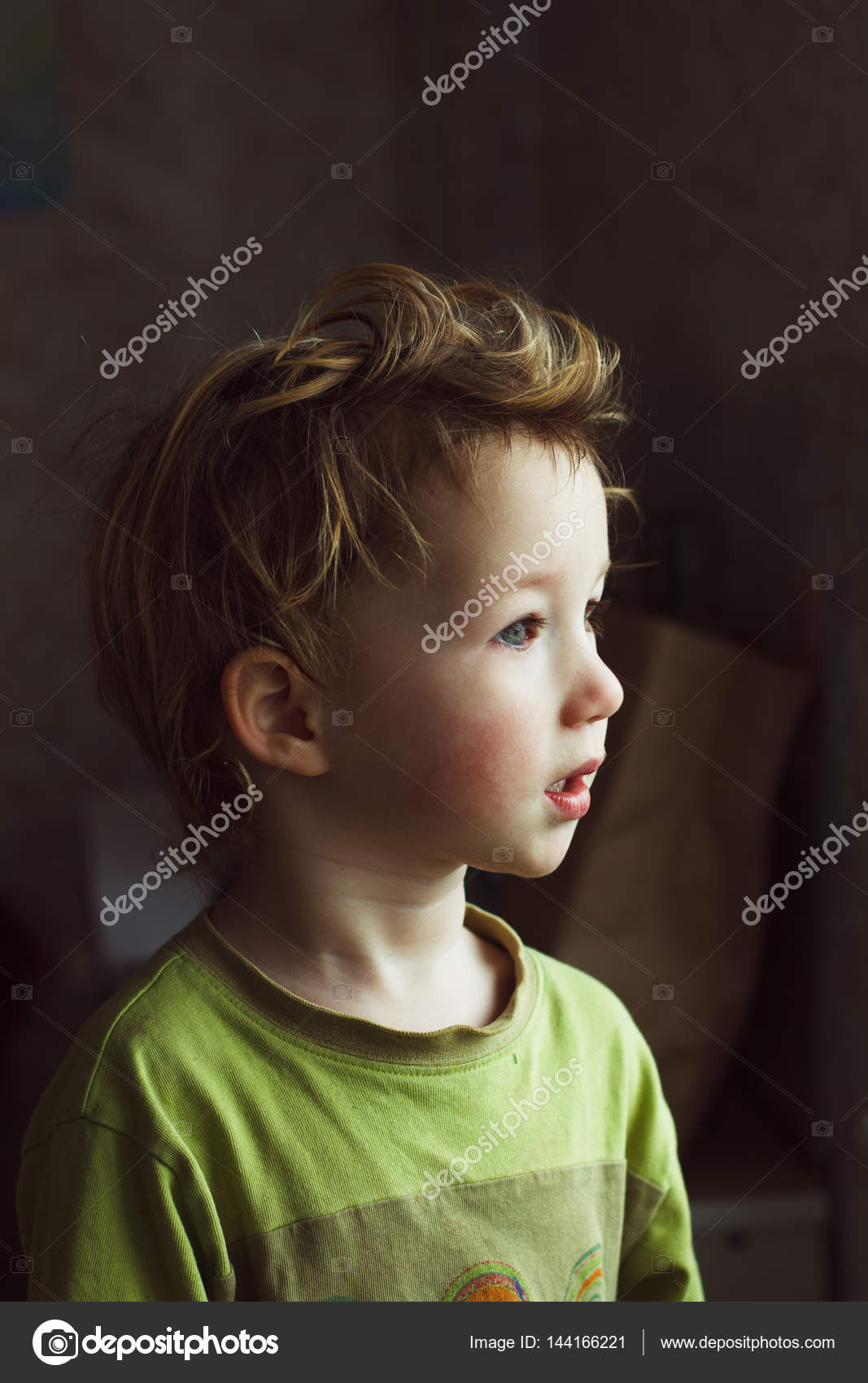 En liten gutt som sitter ved vinduet og tenker på noe. Han har vakkert hår.  Søtt barn. . – stockfoto © ternavskaia.o@gmail.com #144166221, image size:1067x1700