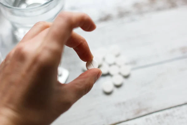 Mano femenina sosteniendo y tomando una píldora blanca de la mesa — Foto de Stock
