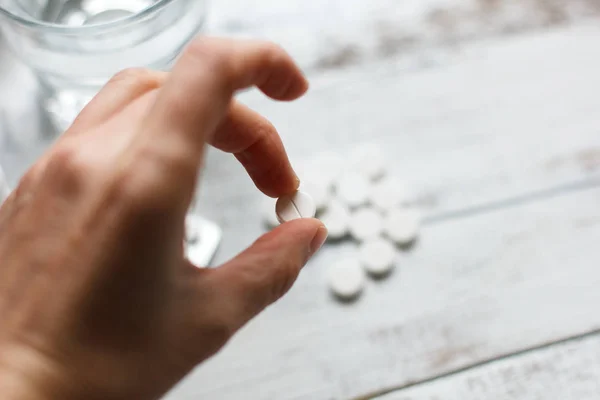 Vrouwelijke hand voorhanden hebben en het nemen van een witte pil uit tabel — Stockfoto